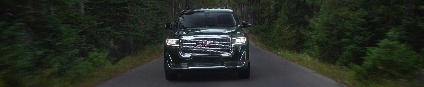 GMC Denali driving through a forest road