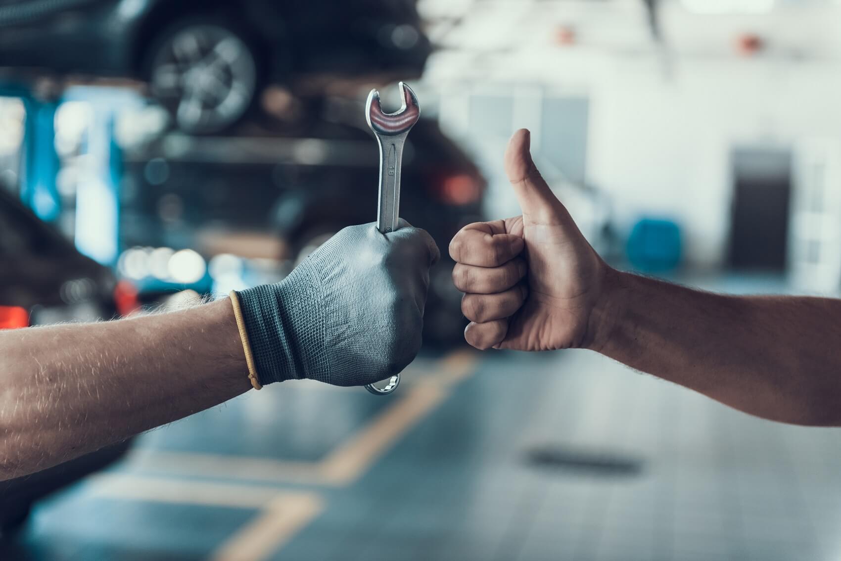 Buick Service Technician Holding a Wrench Next to a Customer with a Thumbs Up